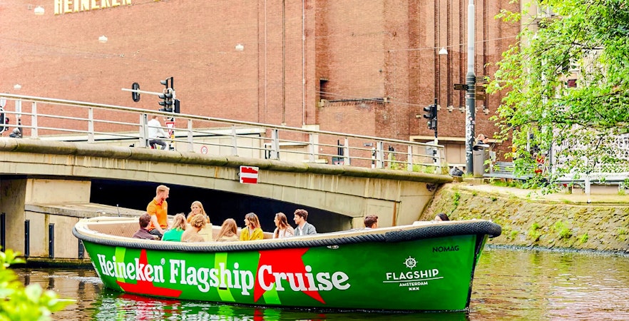 Tourists on Heineken Experience cruise boat in Amsterdam canal.