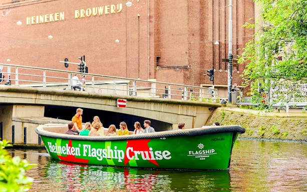 Tourists on Heineken Experience cruise boat in Amsterdam canal.