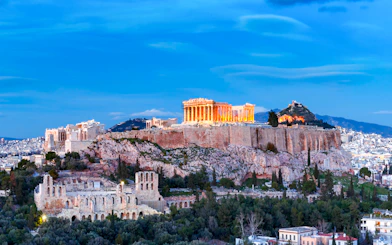 Acropolis illuminated at night during Athens panoramic tour with open double-decker bus.
