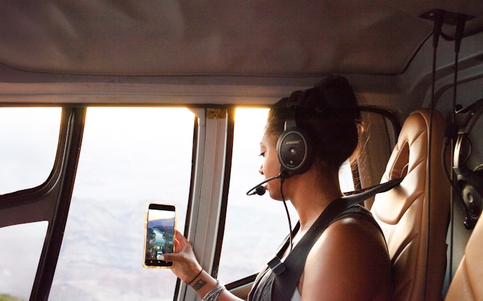 Woman taking a photo from inside a helicopter with a headset on.