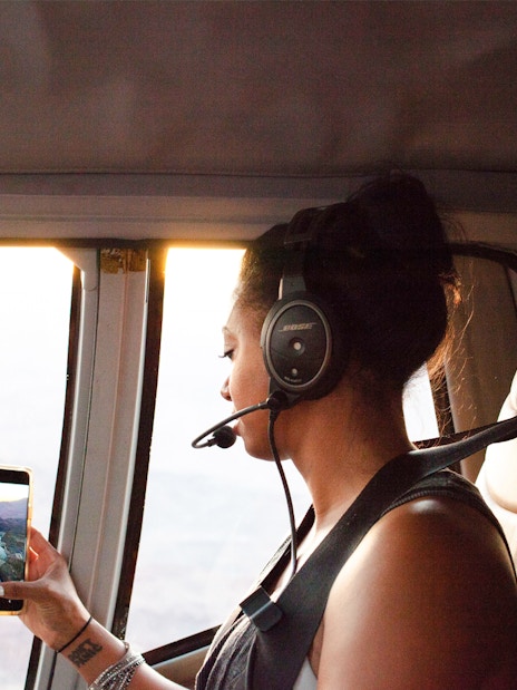 Woman taking a photo from inside a helicopter with a headset on.