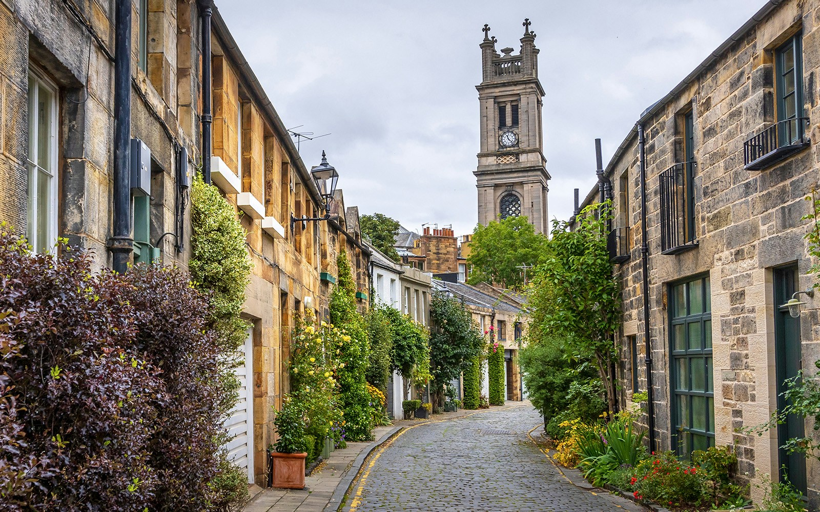 Circus Lane in Stockbridge with cobblestone street and church tower in Edinburgh.