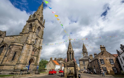 Historic Falkland village square with church and colorful bunting, Scotland.