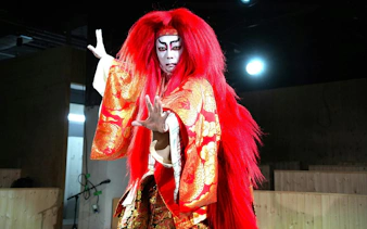 Performer in traditional Japanese Kabuki dance, Renjishi, with red costume and dramatic makeup.