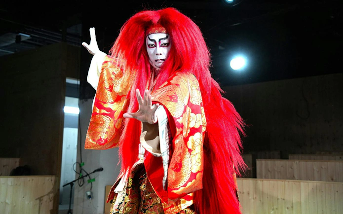 Performer in traditional Japanese Kabuki dance, Renjishi, with red costume and dramatic makeup.