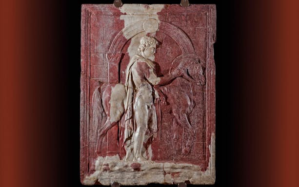 Roman marble relief of a Dioscuro with horse in front of a city gate.