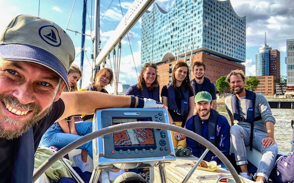 Group enjoying a sailing tour in the Port of Hamburg with Elbphilharmonie in the background.
