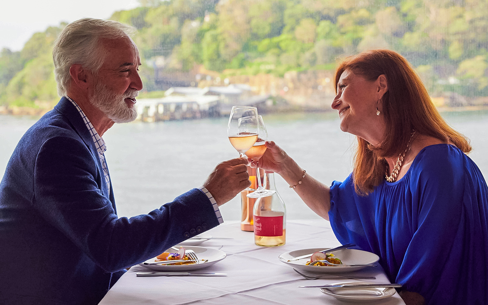 Couple toasting with wine during lunch on a Sydney Harbour cruise.
