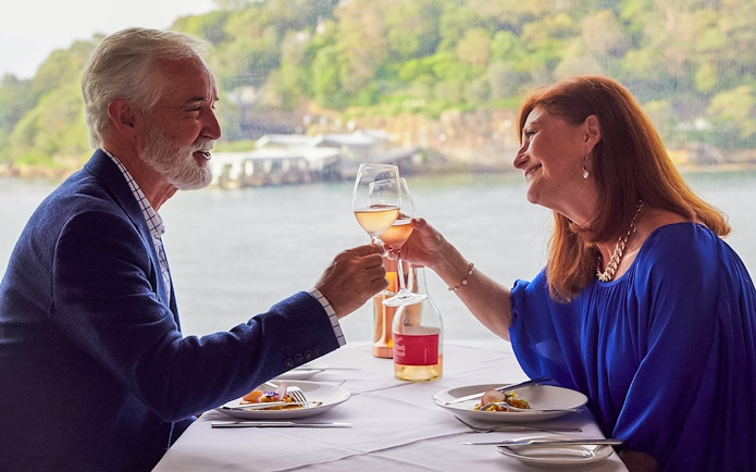 Couple toasting with wine during lunch on a Sydney Harbour cruise.