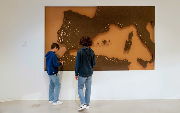 Visitors exploring a cork map of Europe at Planet Cork exhibit.