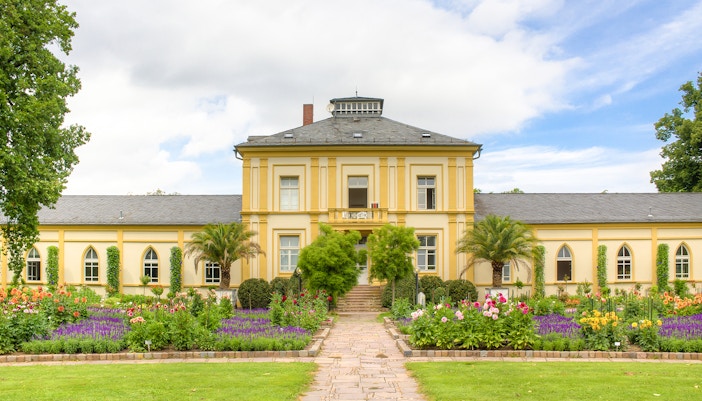 A yellow building with beautiful flowers blooming in the garden, PalmGarten