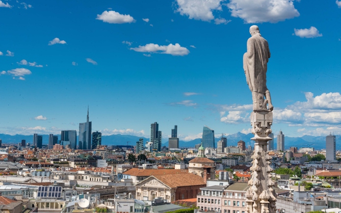 Rooftop view of Milan cityscape from Duomo with skyline and mountains.