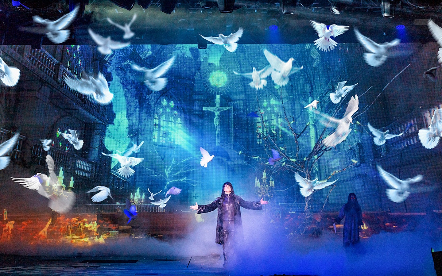 Illusionist on stage with doves and mystical backdrop during Criss Angel Mindfreak show.