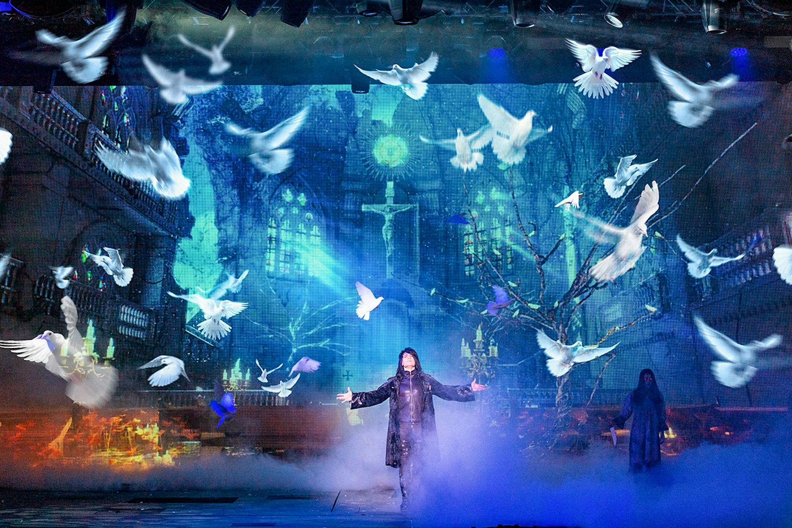 Illusionist on stage with doves and mystical backdrop during Criss Angel Mindfreak show.