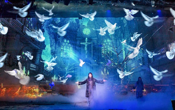 Illusionist on stage with doves and mystical backdrop during Criss Angel Mindfreak show.