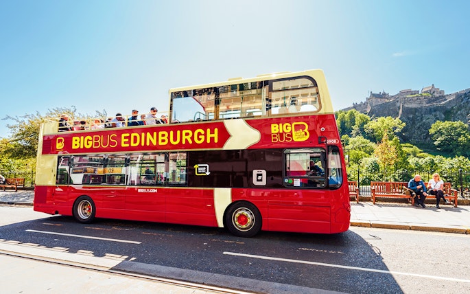 Edinburgh hop-on hop-off bus with Edinburgh Castle in the background.