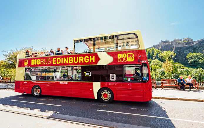Edinburgh hop-on hop-off bus with Edinburgh Castle in the background.