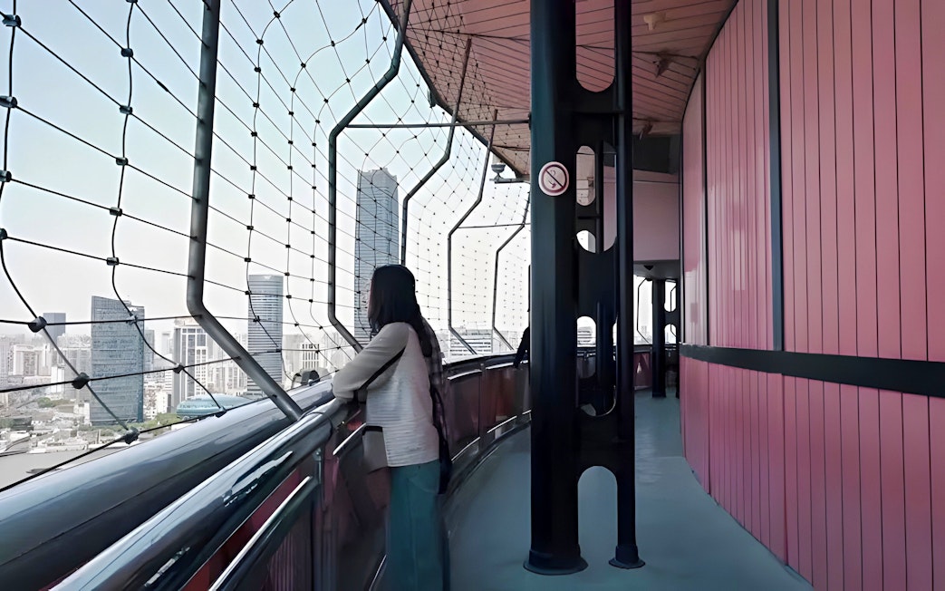 Woman viewing Shanghai skyline from Oriental Pearl Tower observation deck.