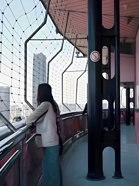 Woman viewing Shanghai skyline from Oriental Pearl Tower observation deck.