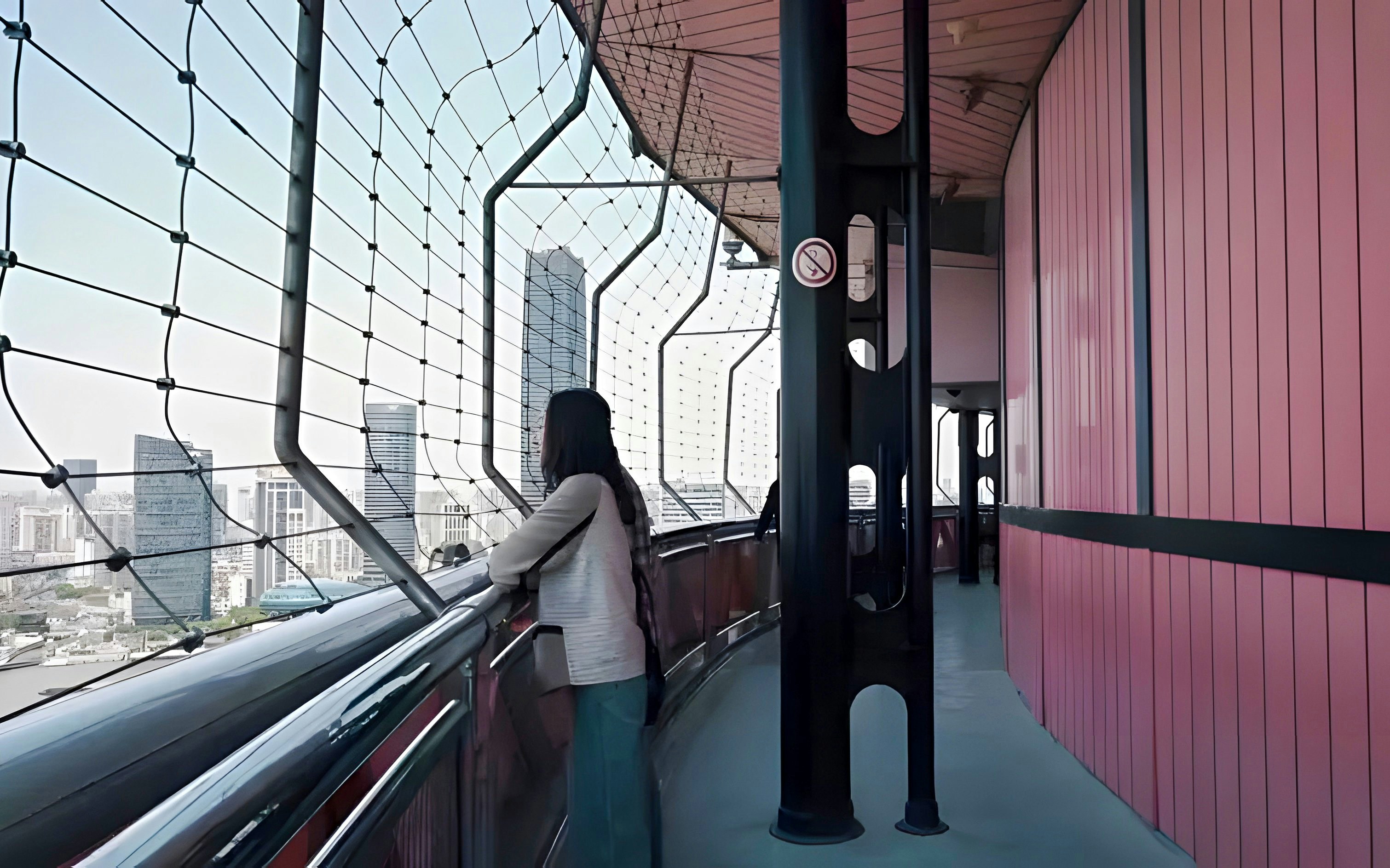 Woman viewing Shanghai skyline from Oriental Pearl Tower observation deck.