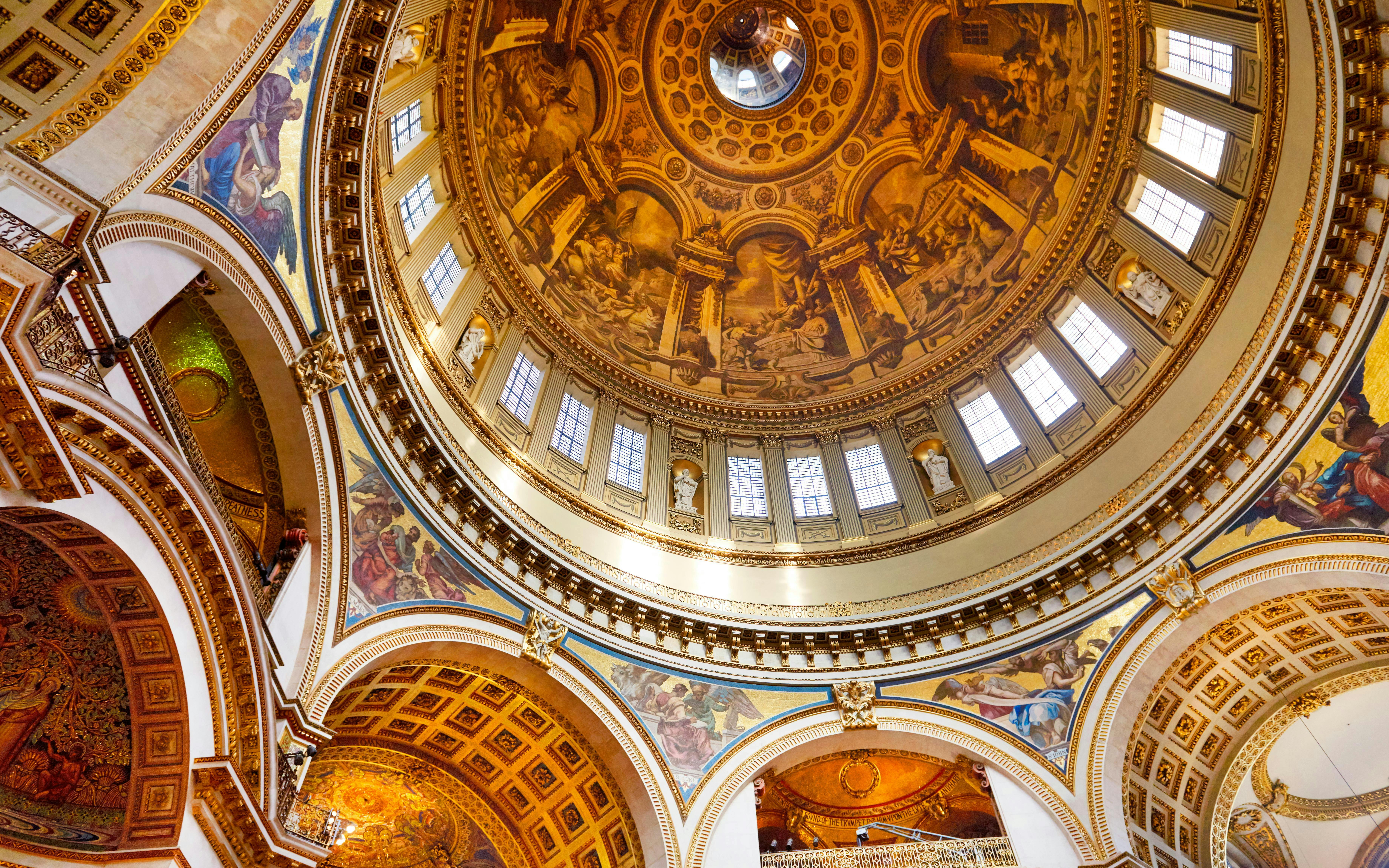 Interior view of St Paul's Cathedral dome with detailed frescoes and ornate architecture.