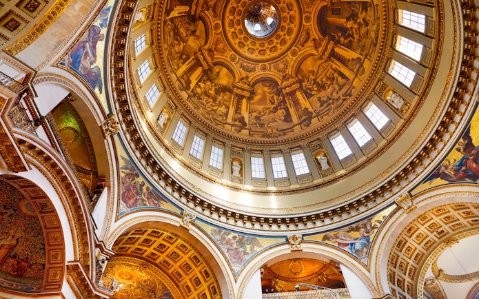 Interior view of St Paul's Cathedral dome with detailed frescoes and ornate architecture.