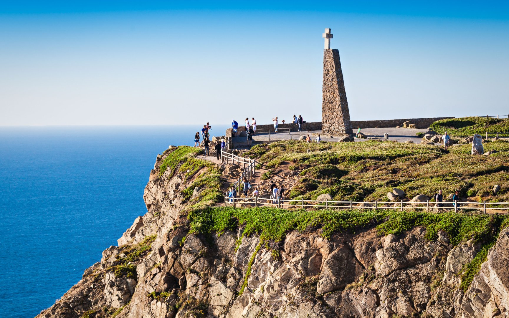 Cabo da Roca cliffside with monument and tourists overlooking the Atlantic Ocean.