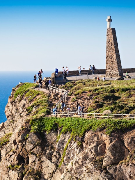 Cabo da Roca cliffside with monument and tourists overlooking the Atlantic Ocean.