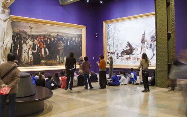 Visitors observing paintings during a guided tour at Musée d’Orsay, Paris.