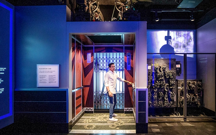 Male tourist entering elevator cab on 2nd floor of Empire State Building exhibition.