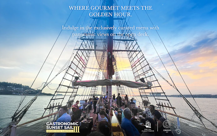 Dinner cruise on The Royal Albatross with guests dining on deck at sunset.