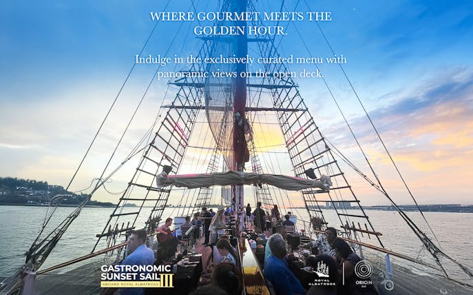 Dinner cruise on The Royal Albatross with guests dining on deck at sunset.