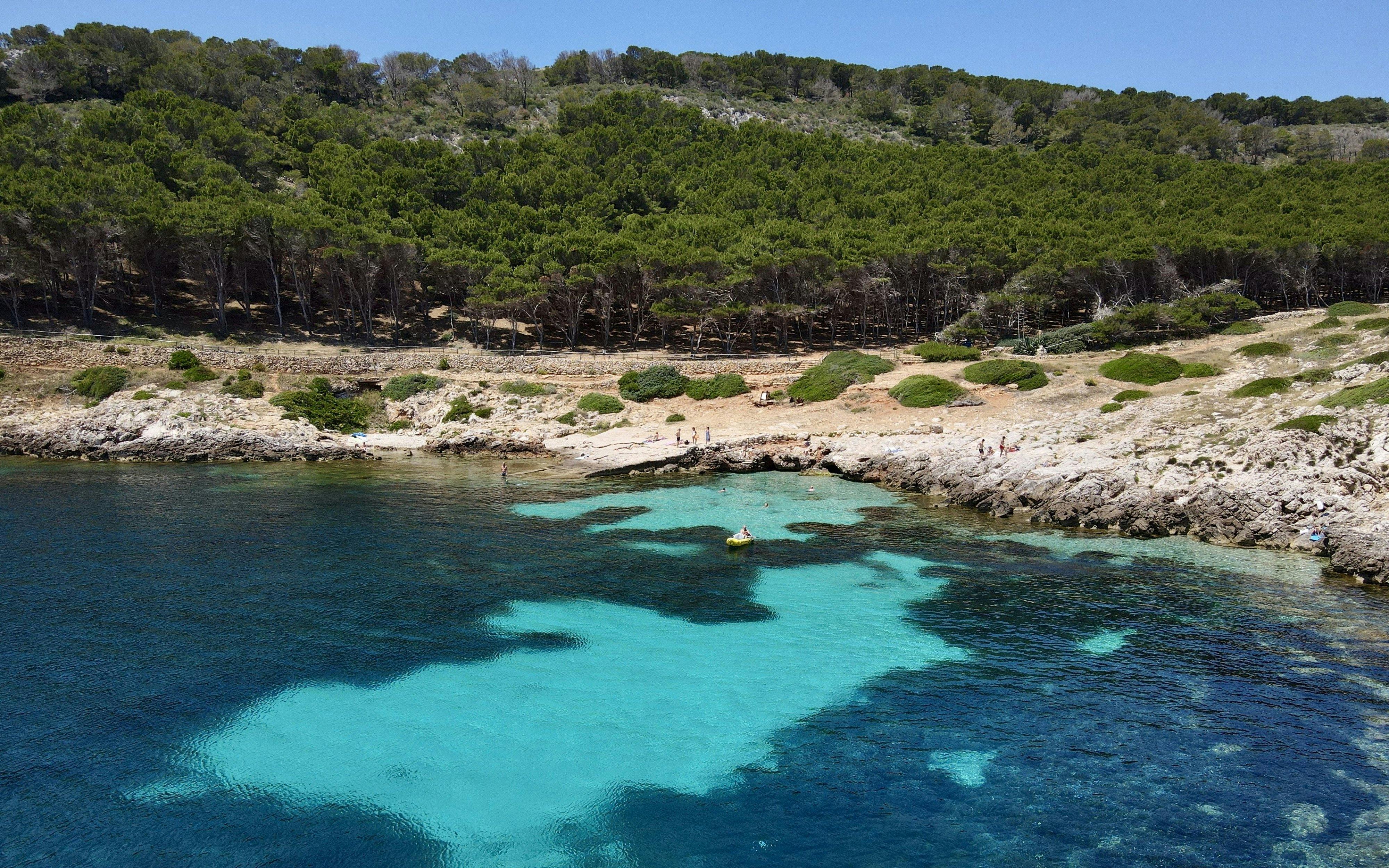 Boat near rocky shore with clear water on Favignana tour from Trapani.