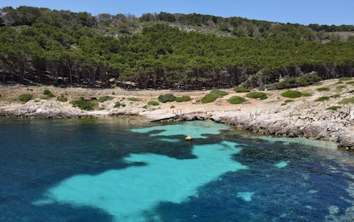 Boat near rocky shore with clear water on Favignana tour from Trapani.