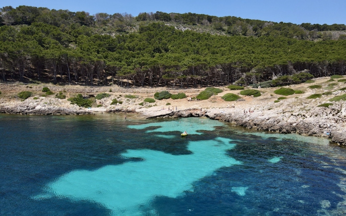 Boat near rocky shore with clear water on Favignana tour from Trapani.
