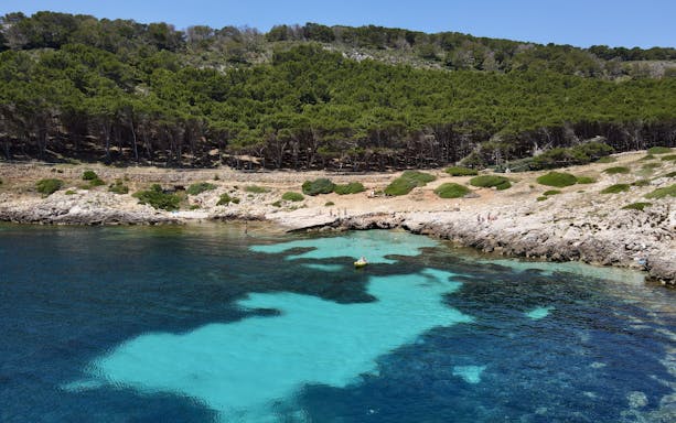 Boat near rocky shore with clear water on Favignana tour from Trapani.