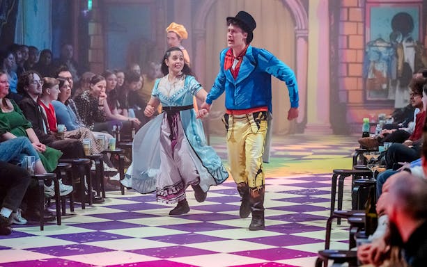 Actors performing "Pride and Prejudice" in colorful costumes on a checkered stage.