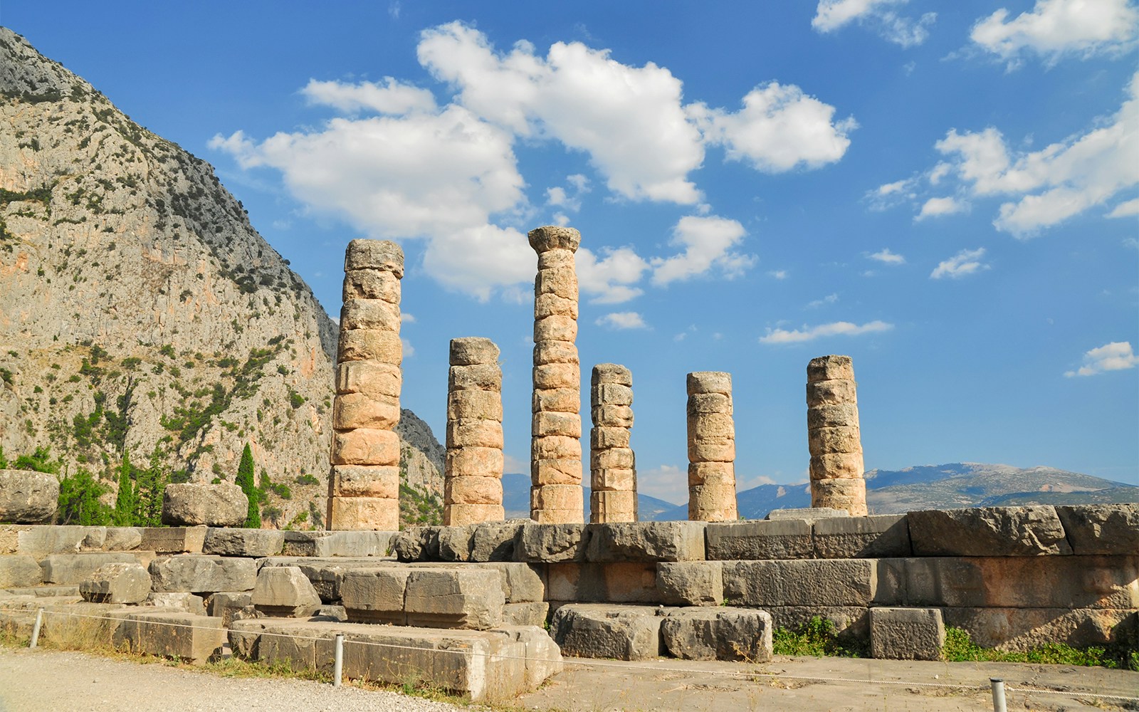 Ruins of the Temple of Apollo at Delphi with mountain backdrop.