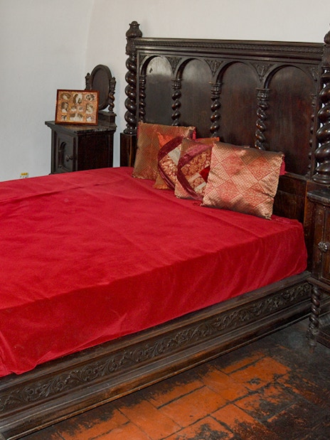 Wooden medieval bed in Bran Castle bedroom with red bedding.