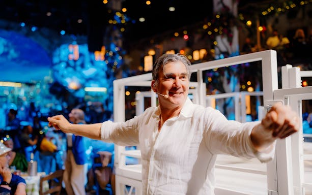 Mamma Mia! The Party stage with performers dancing in a vibrant Greek taverna setting.