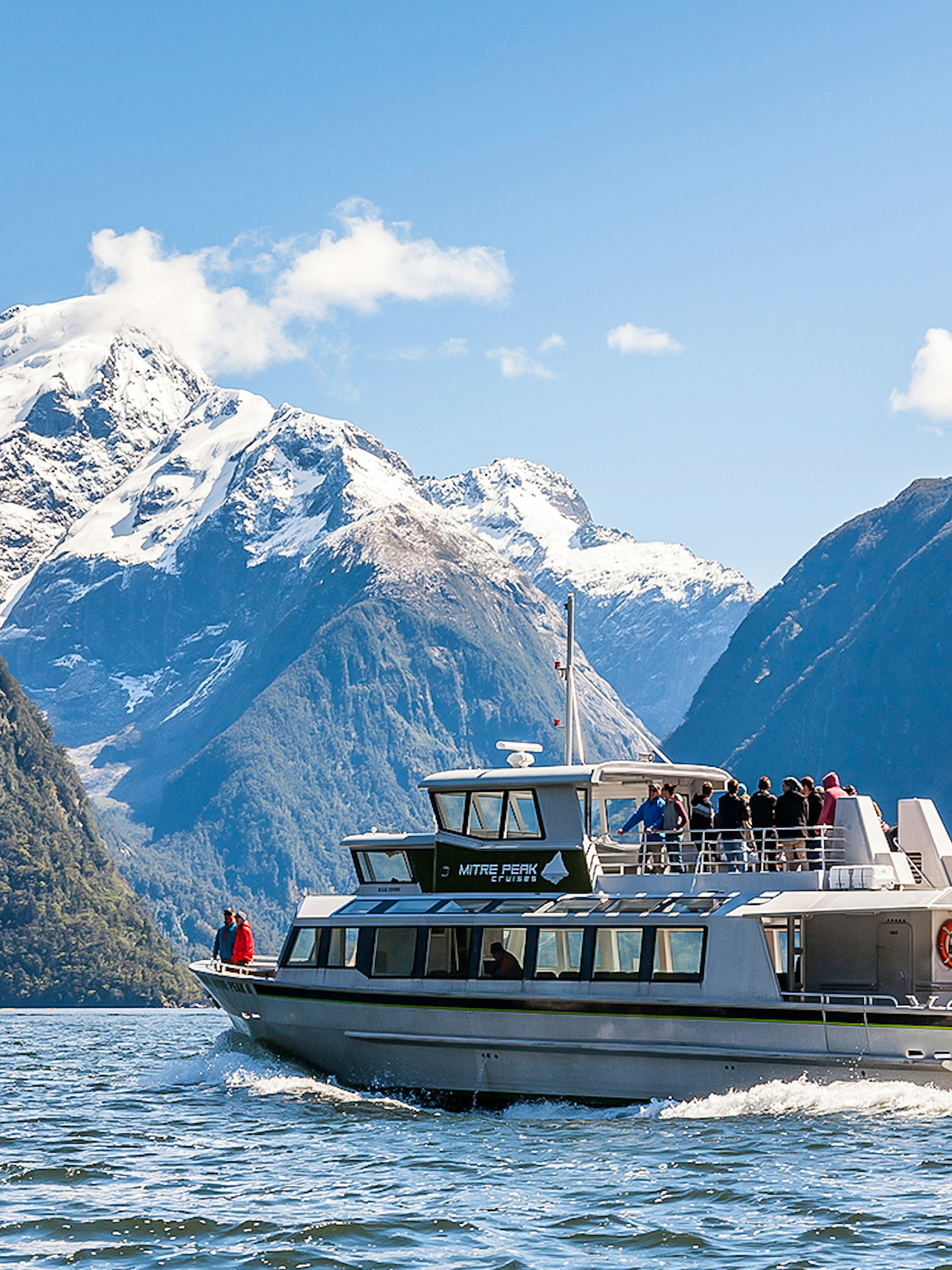 Cruise ship sailing at Milford Sound with Mitre Peak in the background, New Zealand.