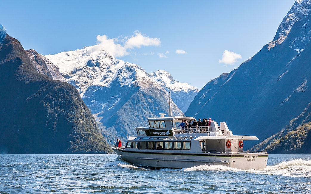 Cruise ship sailing at Milford Sound with Mitre Peak in the background, New Zealand.