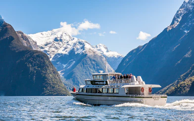 Cruise ship sailing at Milford Sound with Mitre Peak in the background, New Zealand.