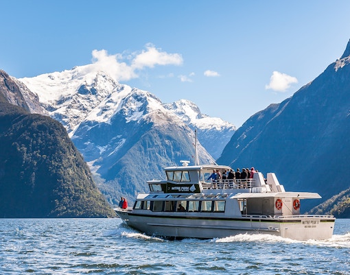 Cruise ship sailing at Milford Sound with Mitre Peak in the background, New Zealand.