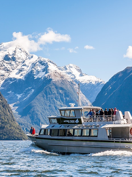 Cruise ship sailing at Milford Sound with Mitre Peak in the background, New Zealand.