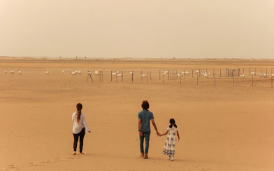 Visitors walking towards a herd of oryx in the desert during a sunrise safari.