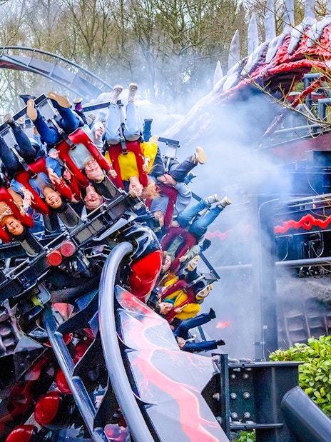 Riders on Nemesis Reborn roller coaster at Alton Towers, upside down on a loop.
