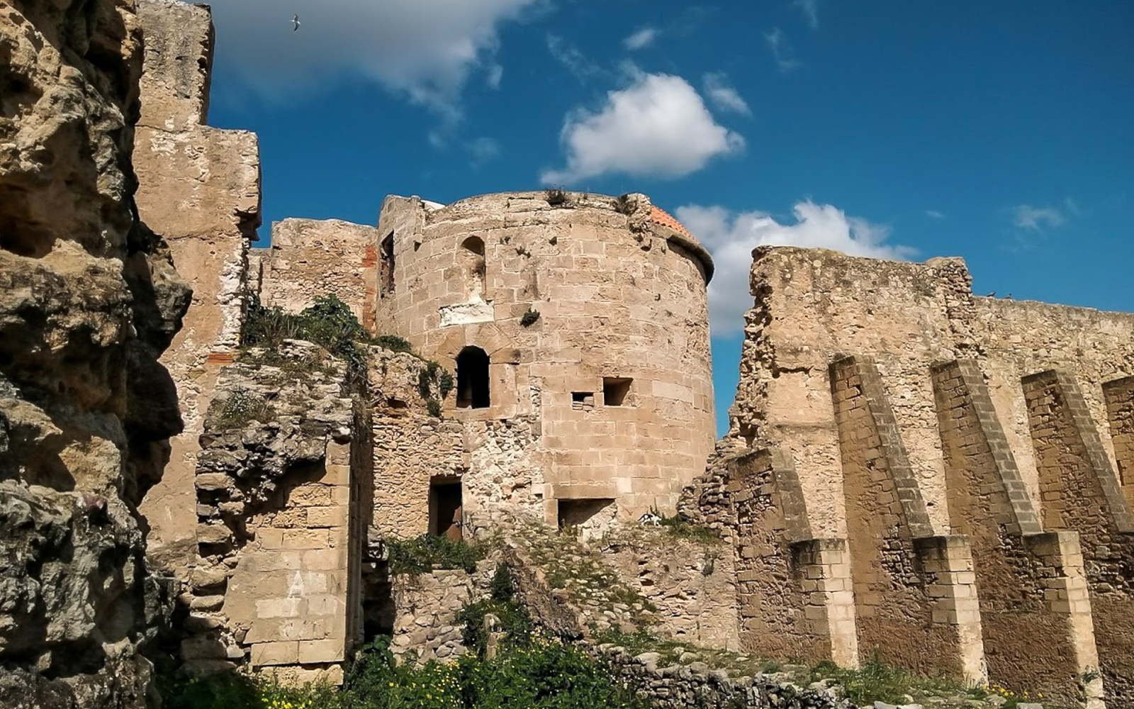 Alghero historic center stone ruins under blue sky.