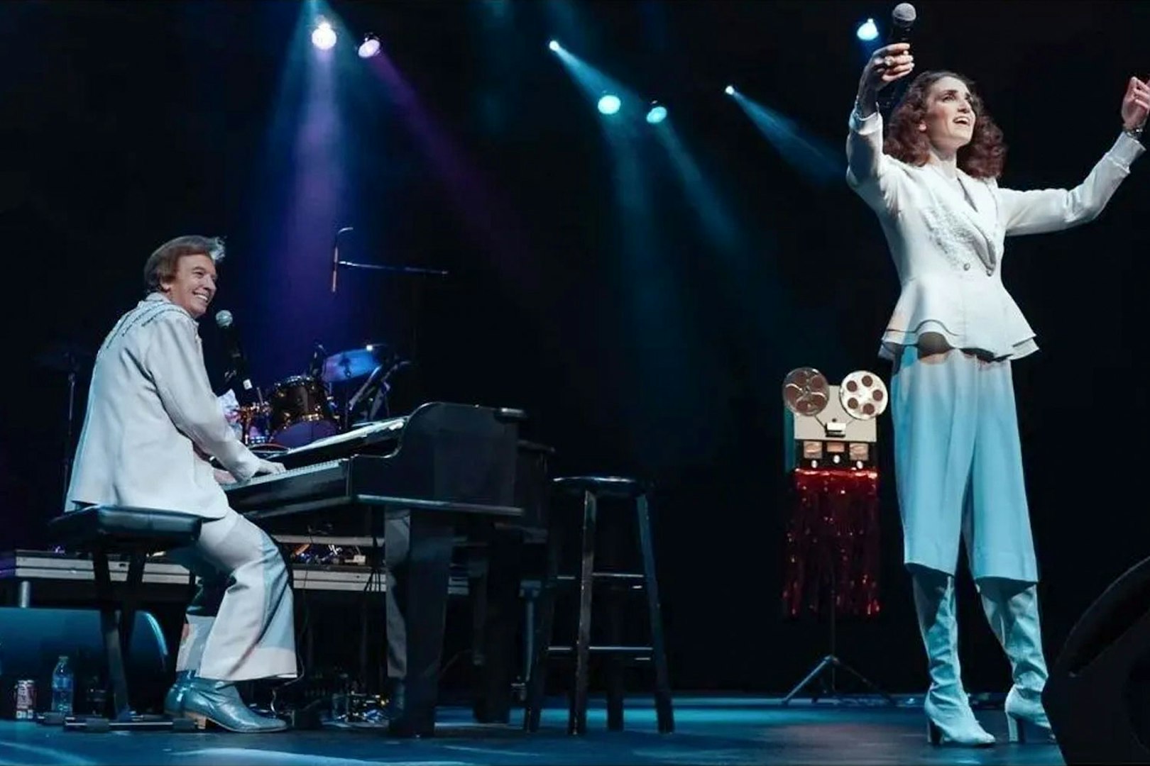 Performers on stage during Carpenters Legacy show, with one playing piano and the other singing.