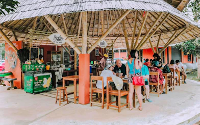 Outdoor dining area in Pita Village near the emerald pool, featuring a bamboo-roofed Thai noodle shop.